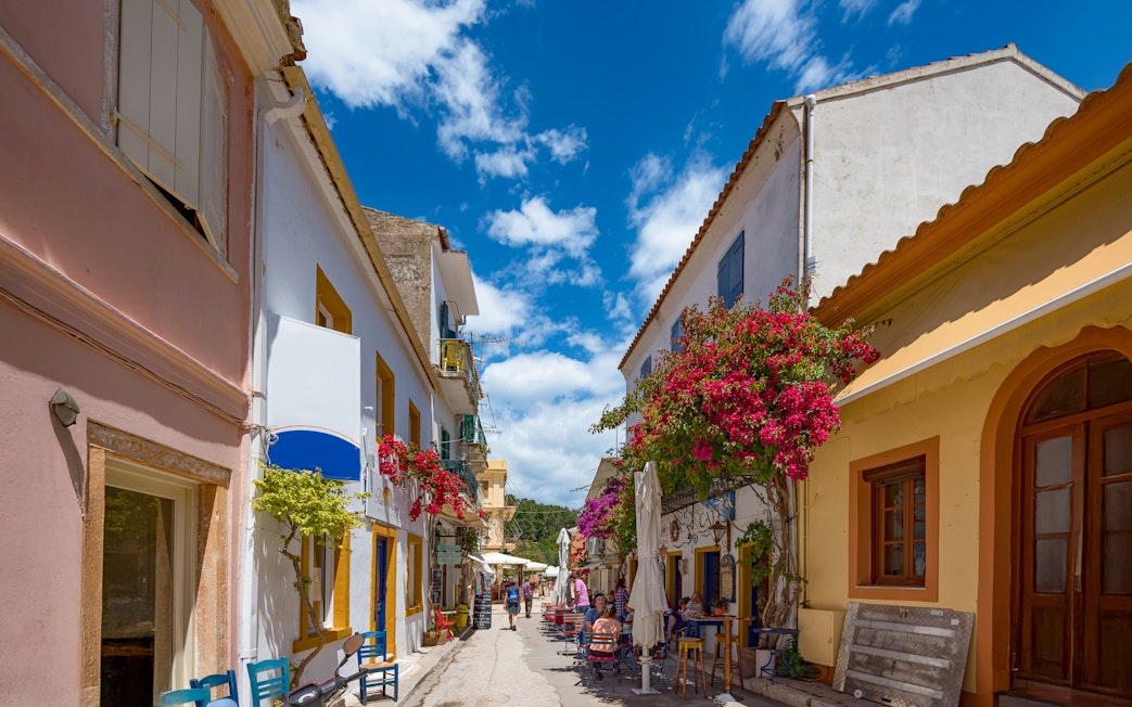 Narrow street with colorful buildings and cafes in Paxos, Ionian Sea, Greece.