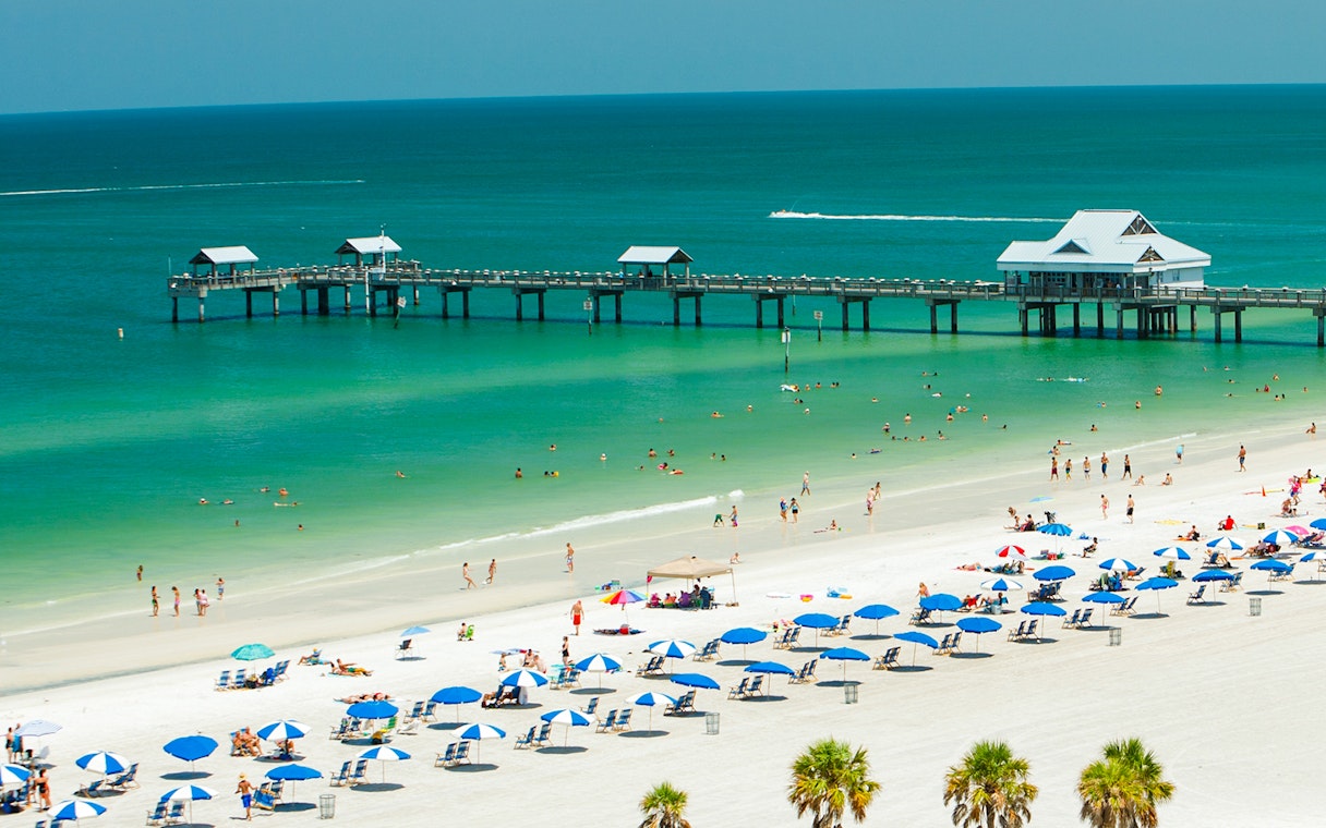 Clearwater Beach with people swimming and sunbathing near a pier, Florida.