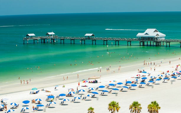 Clearwater Beach with people swimming and sunbathing near a pier, Florida.