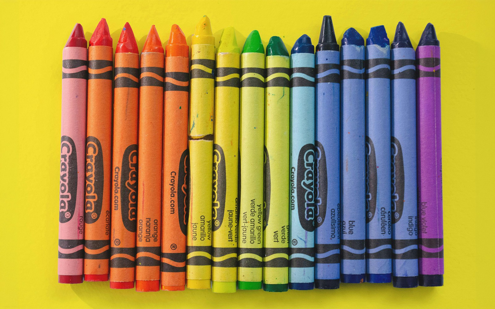 Crayola crayons arranged on a yellow background.