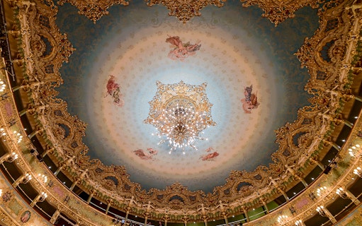 Teatro La Fenice ornate ceiling with chandelier, Venice opera house interior.