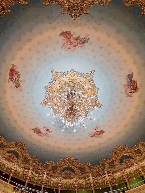 Teatro La Fenice ornate ceiling with chandelier, Venice opera house interior.