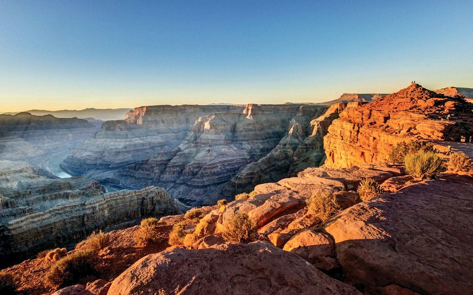Tourists viewing the Grand Canyon West Rim from an observation point with a clear sky.