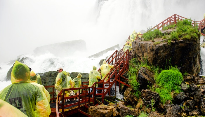 Visitors in raincoats on wooden platform at Cave of the Winds, Niagara Falls.