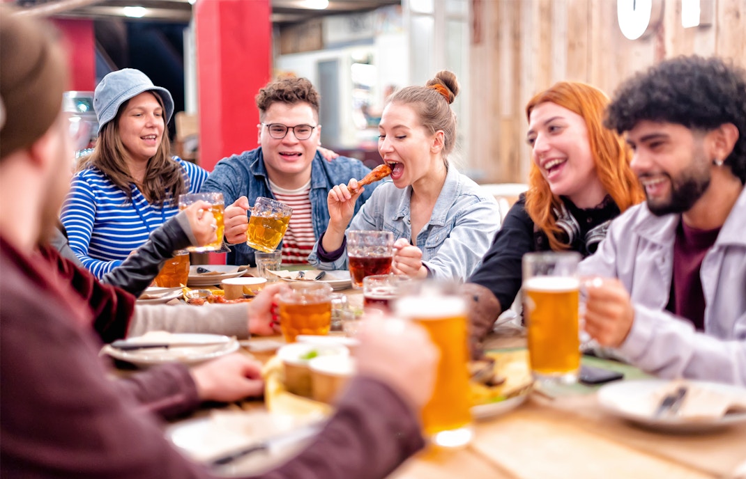 Group enjoying drinks and food at a lively pub in a social setting.