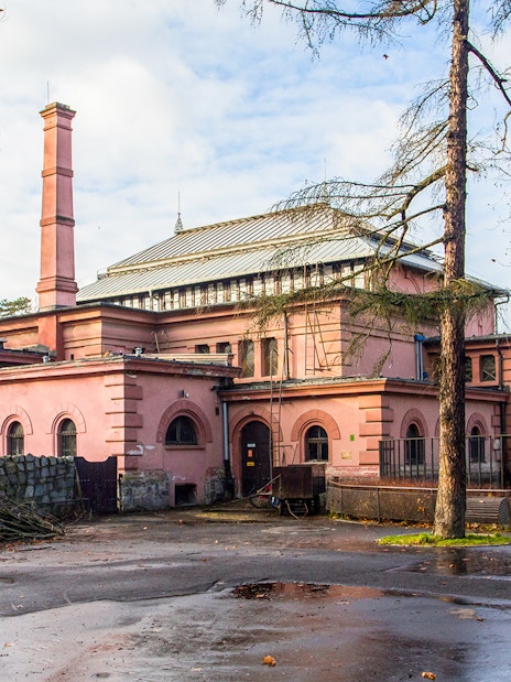 Historic building at Wroclaw Zoo, Poland, surrounded by trees and a wet pathway.
