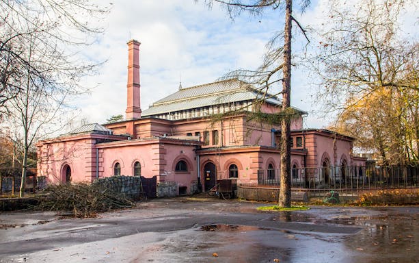 Historic building at Wroclaw Zoo, Poland, surrounded by trees and a wet pathway.