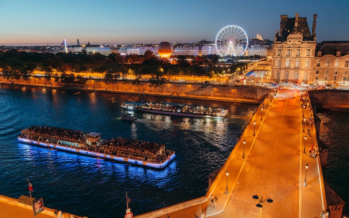 Evening Seine River cruise with illuminated boats near Paris landmarks.