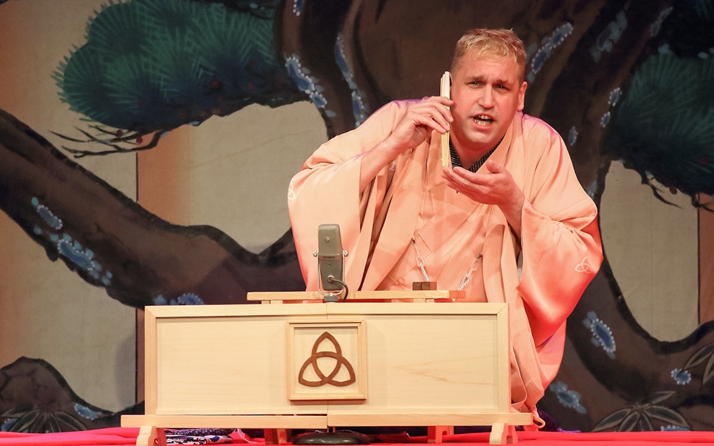 Performer in traditional attire delivering Rakugo storytelling on stage.