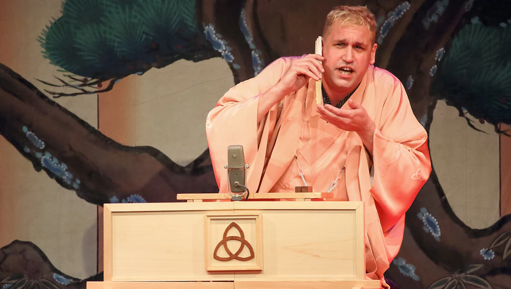 Performer in traditional attire delivering Rakugo storytelling on stage.