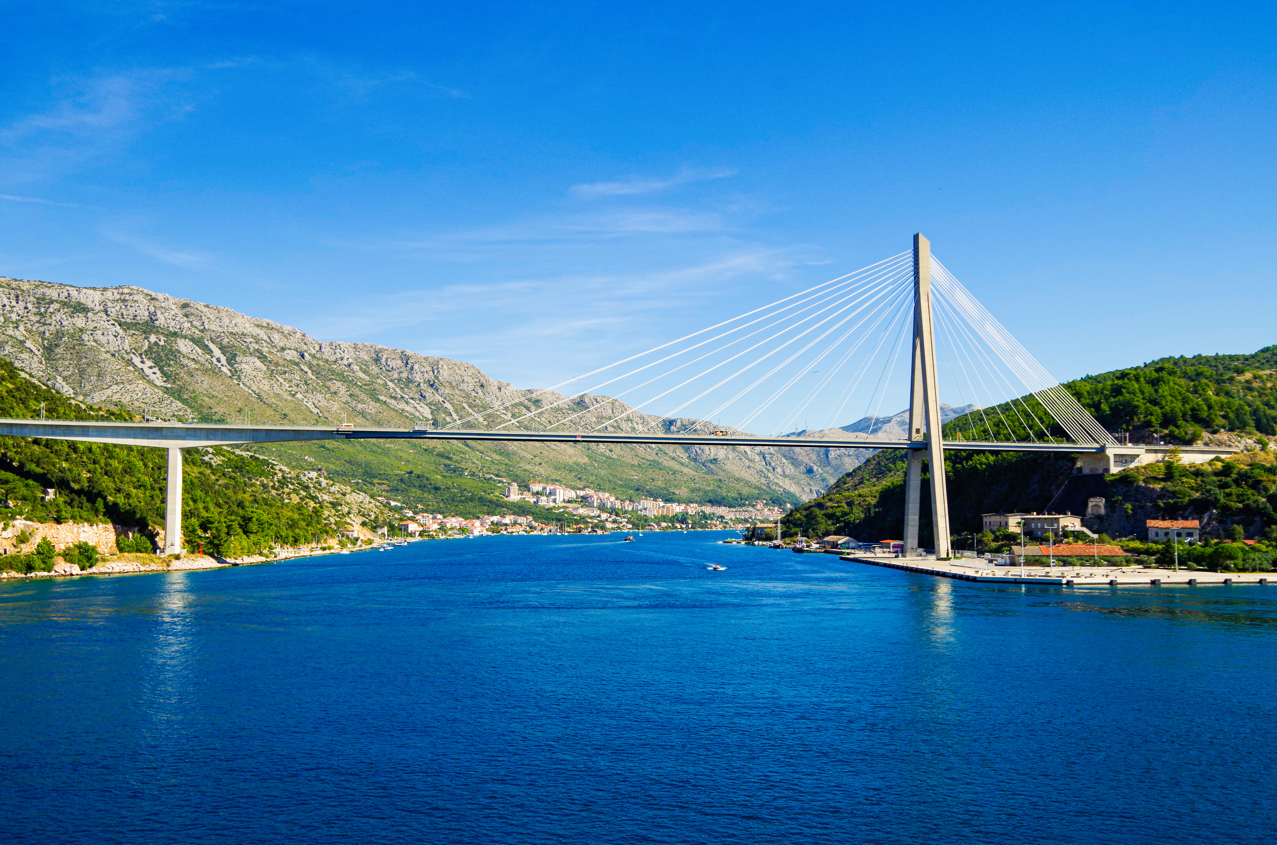 Franjo Tudman Bridge spanning over Dubrovnik's scenic coastline with boats in the Adriatic Sea.