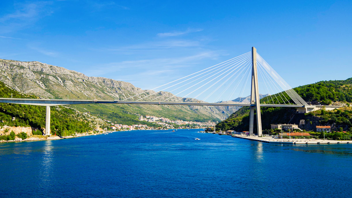 Franjo Tudman Bridge spanning over Dubrovnik's scenic coastline with boats in the Adriatic Sea.