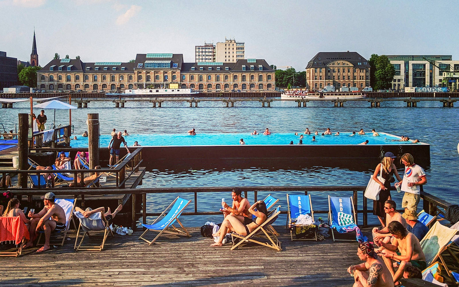 Badeschiff Berlin floating pool on River Spree with city skyline in background.