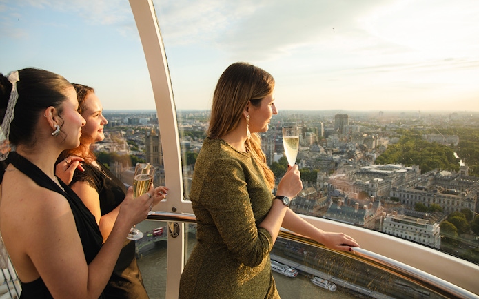 Women enjoying champagne on the London Eye with cityscape views.