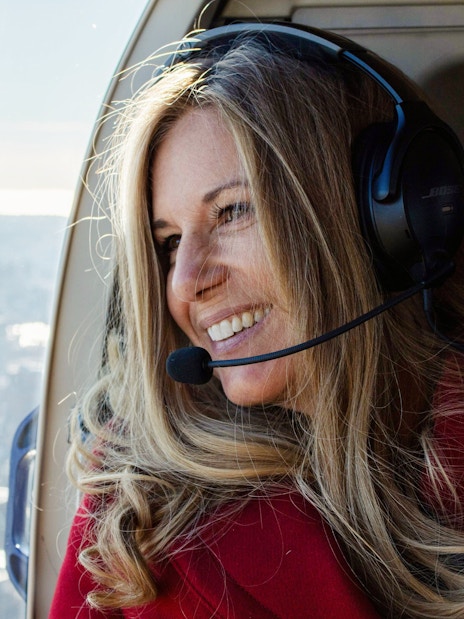 Woman enjoying helicopter tour over New York City skyline.