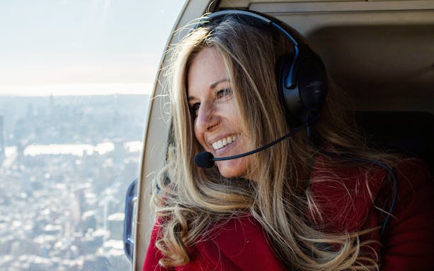 Woman enjoying helicopter tour over New York City skyline.