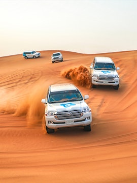 SUVs driving through sand dunes during a desert safari in Dubai.