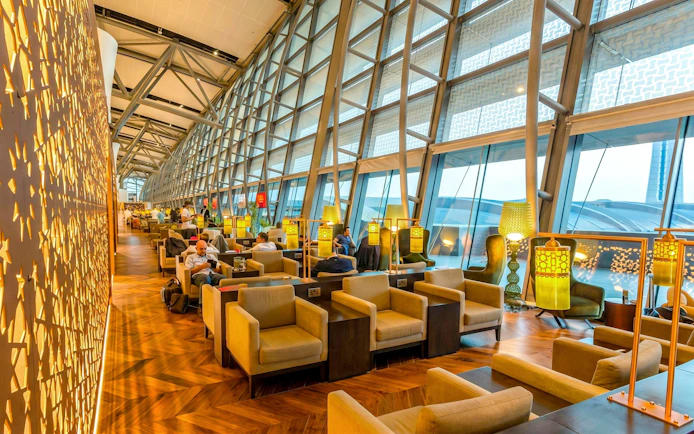 Primeclass Lounge seating area at Muscat International Airport departures, featuring modern decor and large windows.