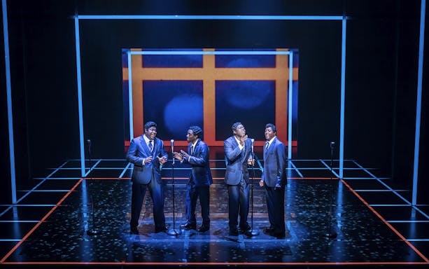 Four performers singing on stage in "The Drifters Girl" musical.