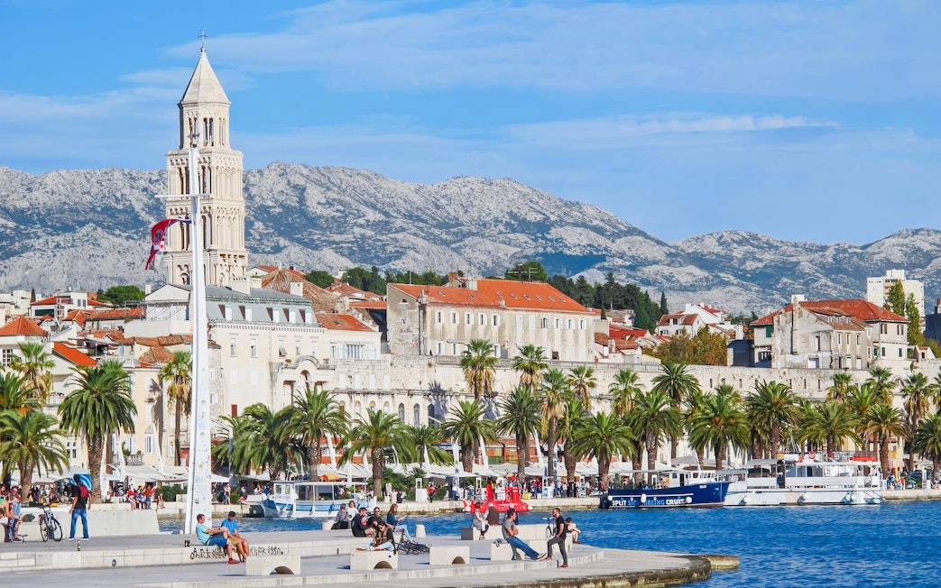 Riva waterfront promenade with Diocletian's Palace and mountains in Split, Croatia.