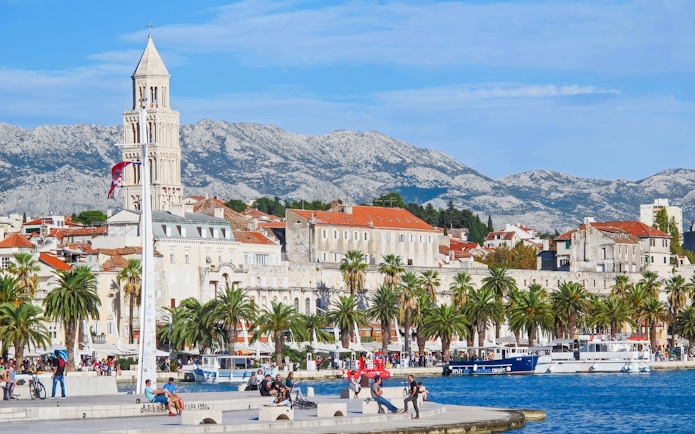 Riva waterfront promenade with Diocletian's Palace and mountains in Split, Croatia.