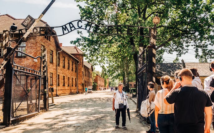 Visitors at Auschwitz-Birkenau entrance during guided tour, Poland.