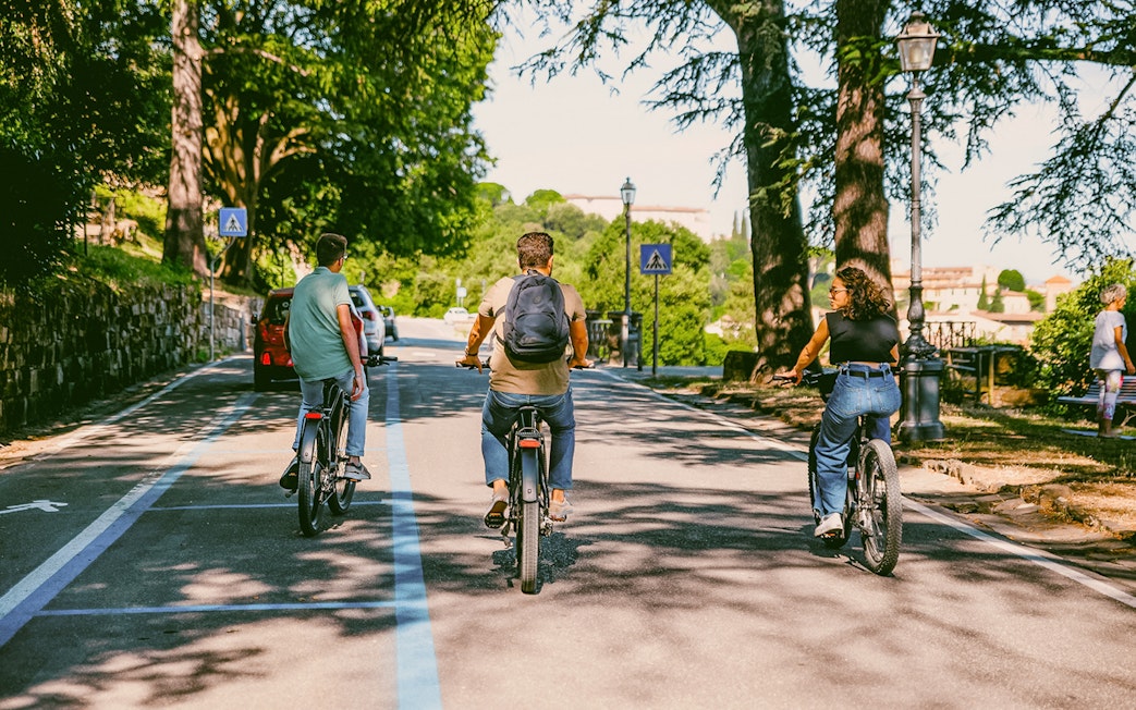 Cyclists riding e-bikes through Florence hills on a sunny day.
