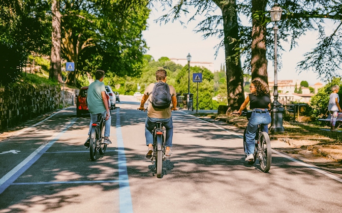 Cyclists riding e-bikes through Florence hills on a sunny day.