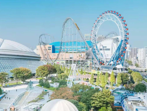 Tokyo Dome and amusement park with roller coaster and Ferris wheel in Tokyo, Japan.