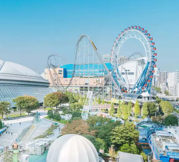 Tokyo Dome and amusement park with roller coaster and Ferris wheel in Tokyo, Japan.