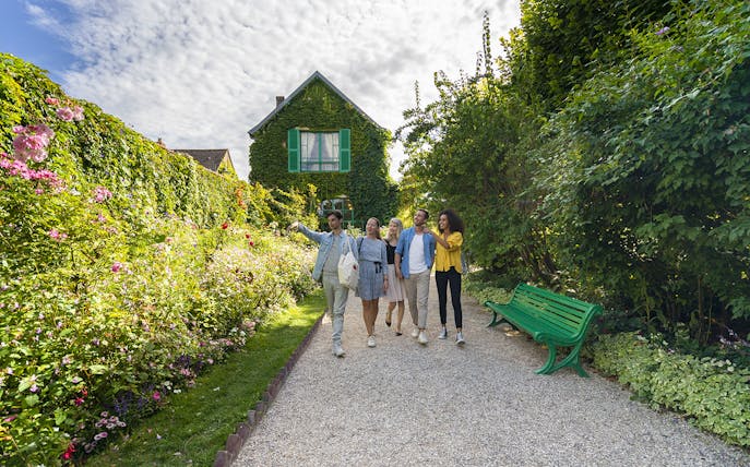 Visitors exploring Giverny Garden with a guide, surrounded by lush greenery and flowers.