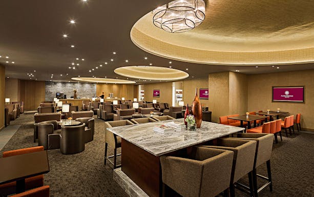 Plaza Premium First lounge seating area with tables and chairs in departures.