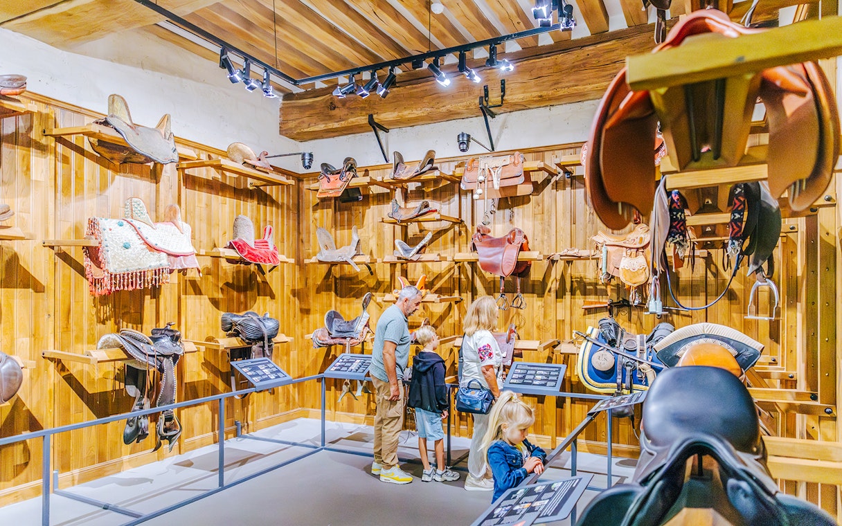 Visitors exploring the saddle room at Chateau of Chantilly.