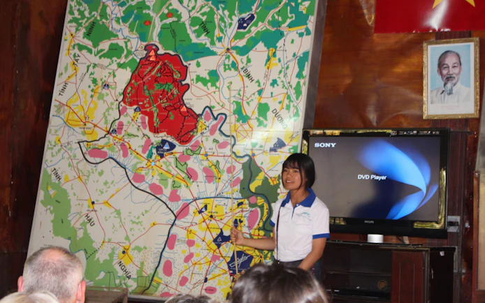 Guide explaining Cu Chi Tunnels map during VIP speed boat tour in Vietnam.