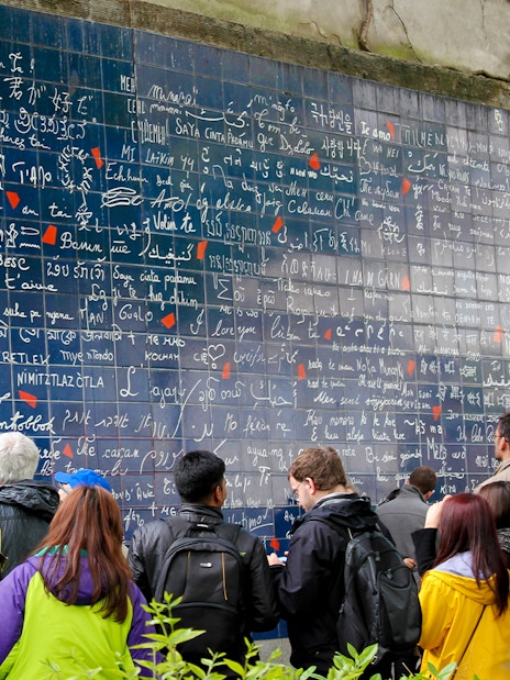 Visitors viewing the Wall of Love in Montmartre, Paris, with "I love you" in multiple languages.