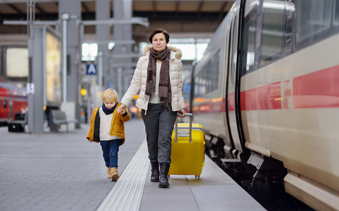 Grandmother and child at Swiss train station with luggage.