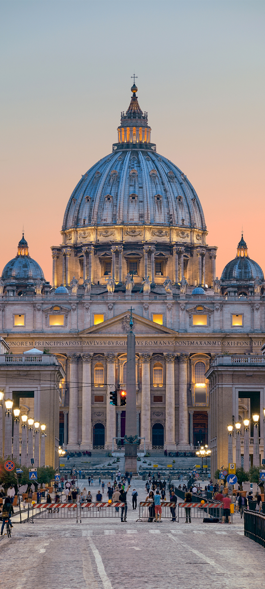 St. Peter's Basilica illuminated at dusk with vibrant sky in Rome.