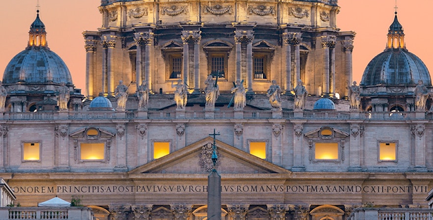 St. Peter's Basilica illuminated at dusk with vibrant sky in Rome.