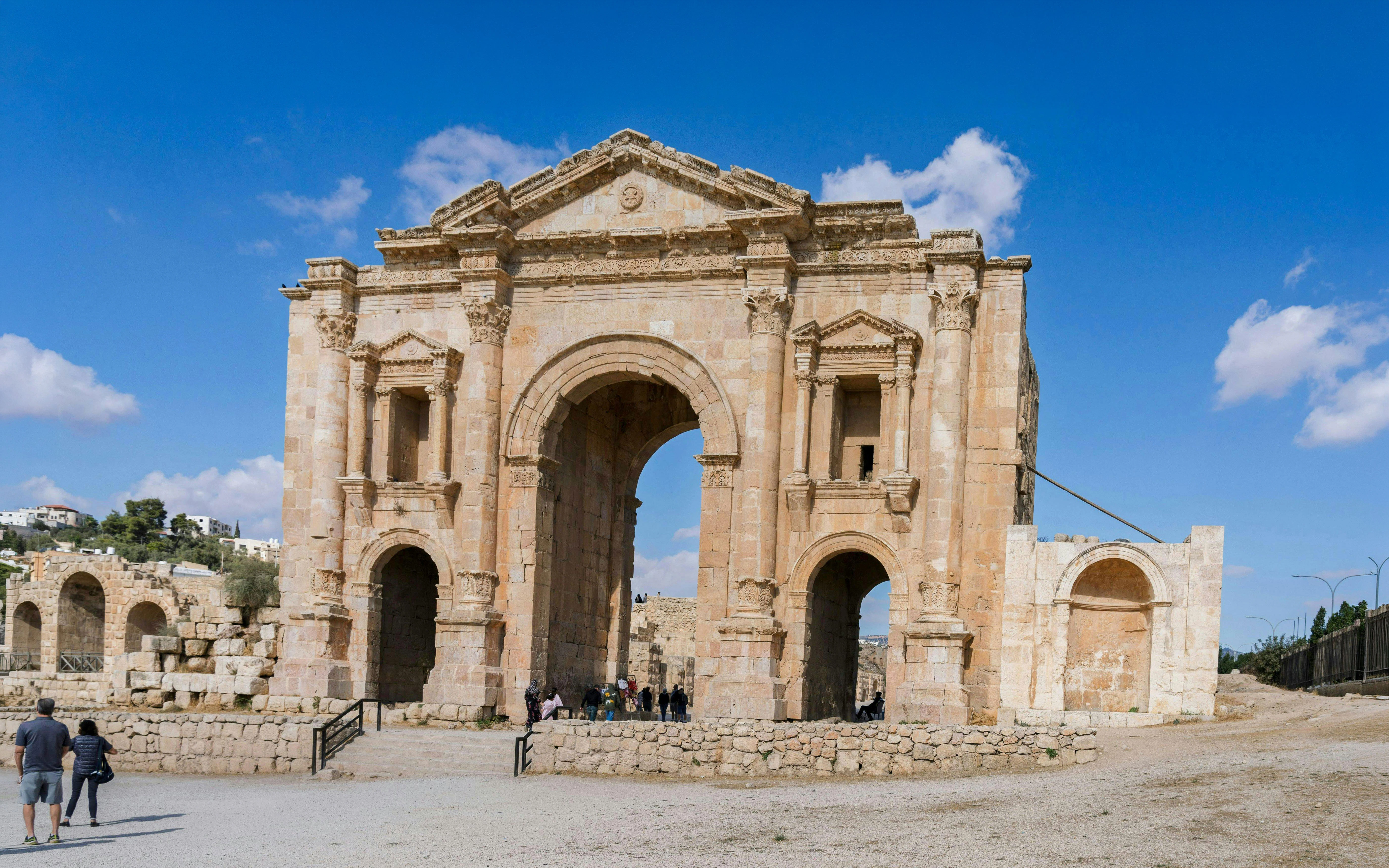 Hadrian's Arch in Jerash, ancient Roman gateway with tourists exploring.