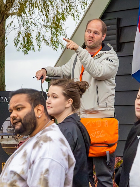 Tour guide leading visitors at Keukenhof with Dutch flag in background.