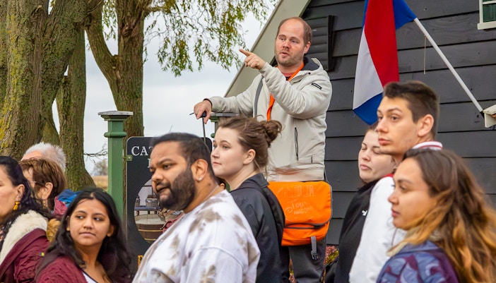 Visitors exploring vibrant tulip fields at Keukenhof Gardens, Netherlands, with a traditional windmill in the background.