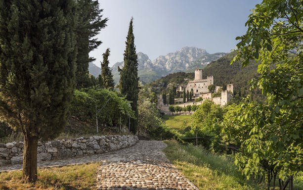 Avio Castle surrounded by trees and mountains in Trentino, Italy.