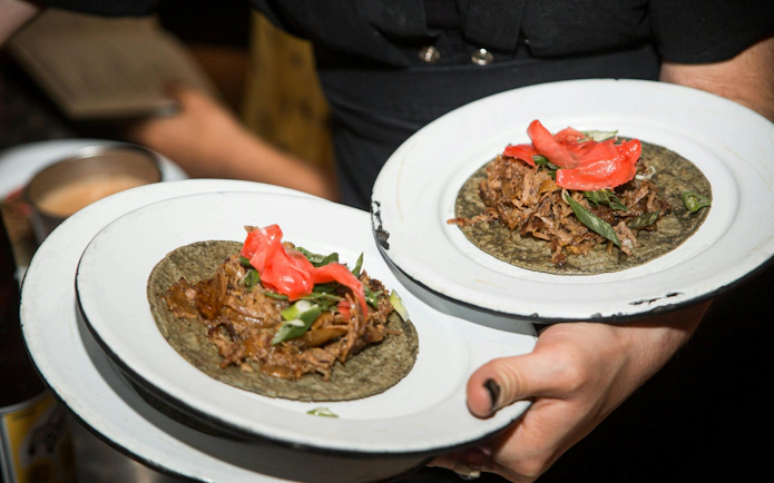 Tacos with shredded meat and vegetables served on a plate in Mexico City.