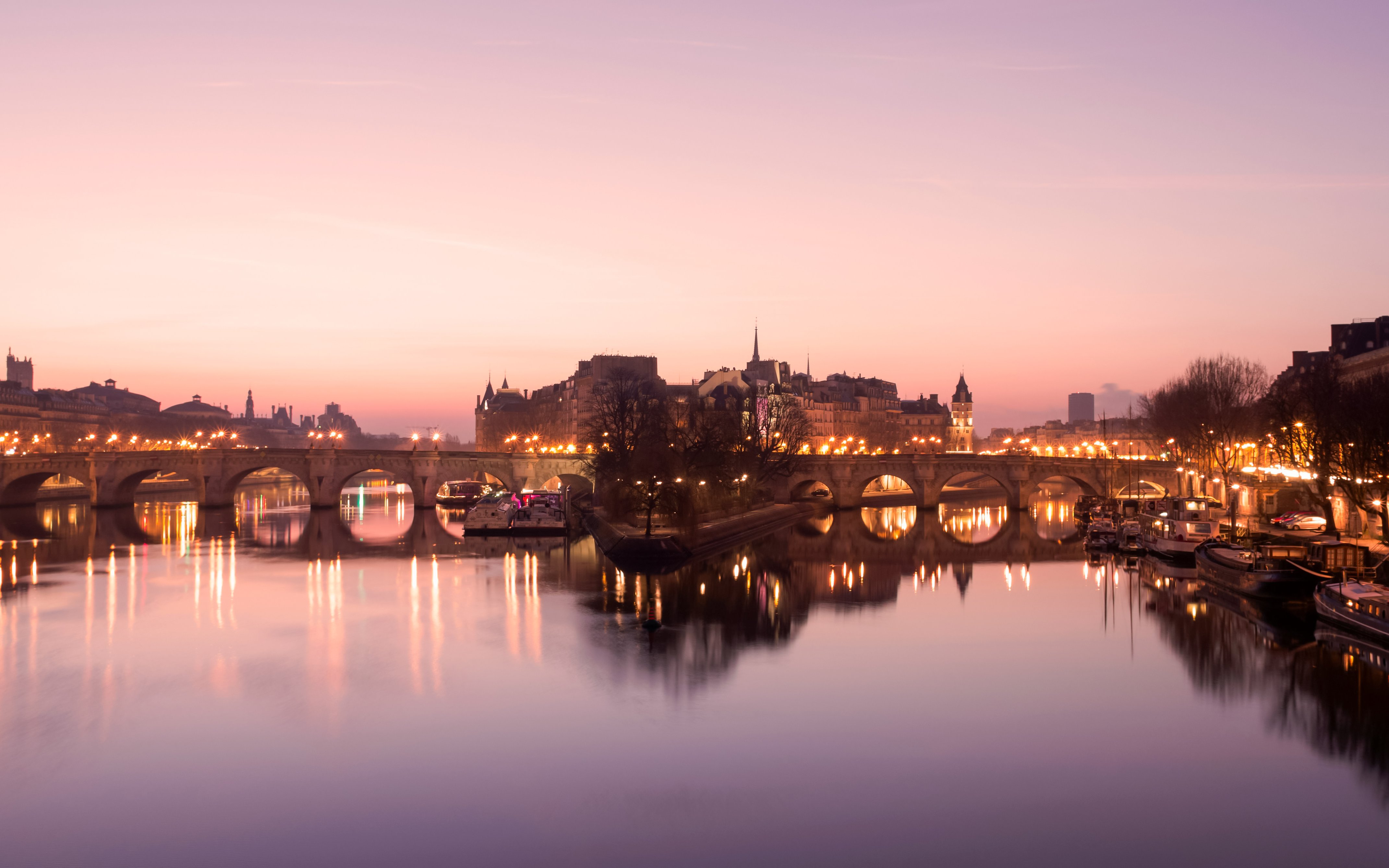 Paris evening skyline with illuminated bridge over the Seine River.