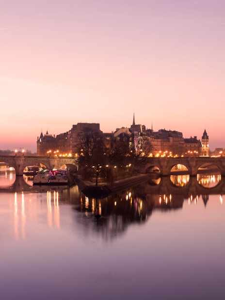 Paris evening skyline with illuminated bridge over the Seine River.