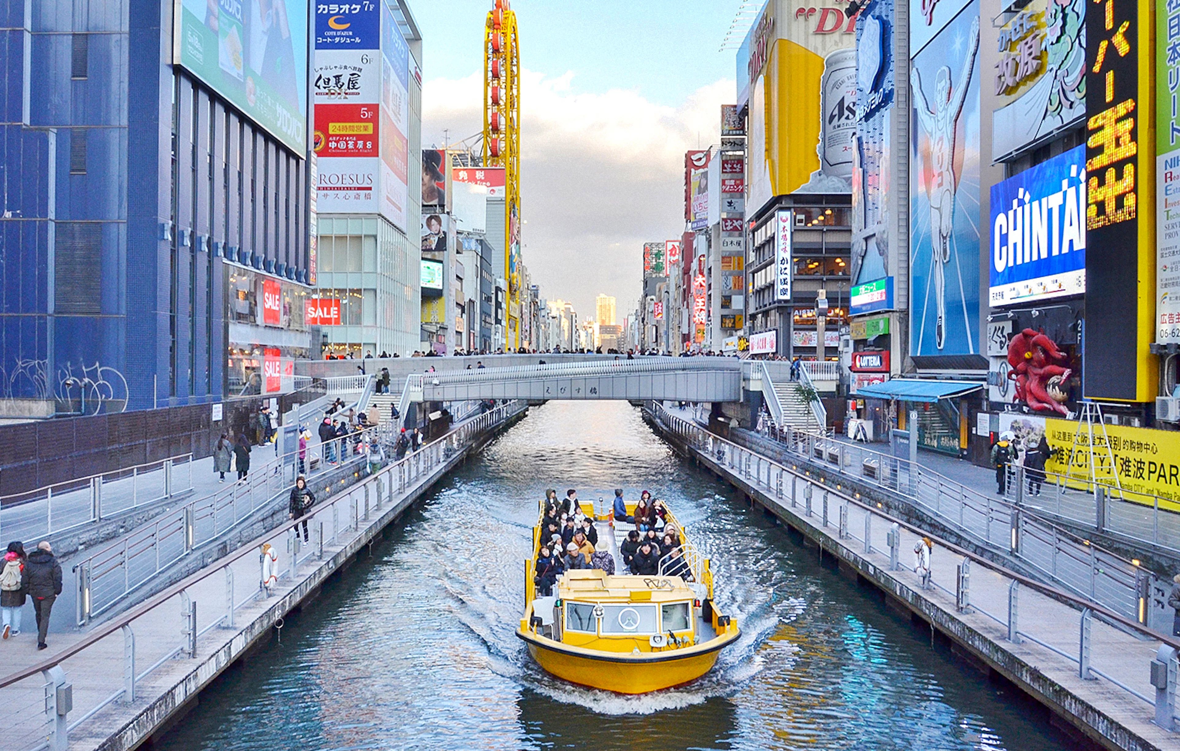 Tombori River Cruise boat navigating through Osaka's vibrant Dotonbori district.