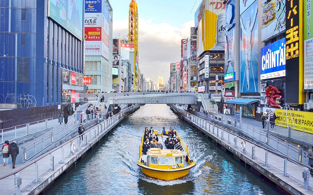 Tombori River Cruise boat navigating through Osaka's vibrant Dotonbori district.