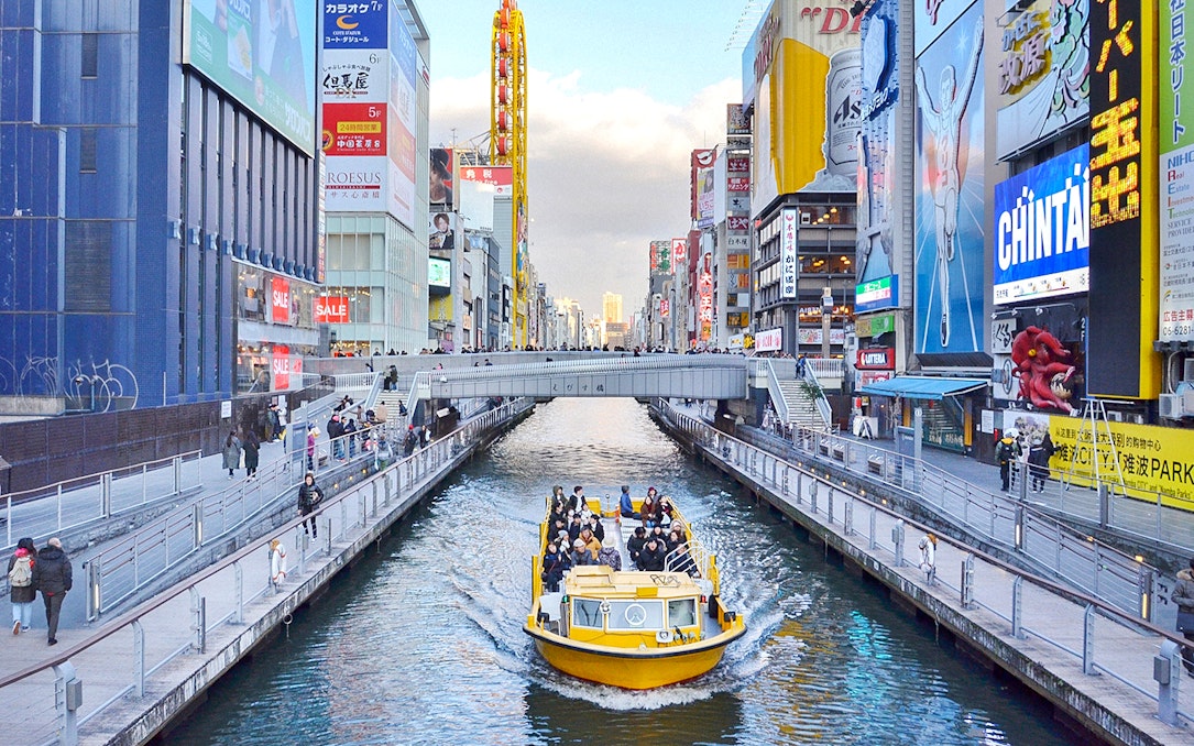 Tombori River Cruise boat navigating through Osaka's vibrant Dotonbori district.