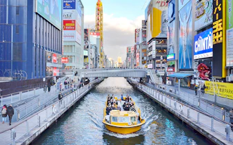 Tombori River Cruise boat navigating through Osaka's vibrant Dotonbori district.