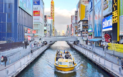 Tombori River Cruise boat navigating through Osaka's vibrant Dotonbori district.